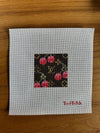 Cross-stitched design on fabric with 'Bad Bitch' text, placed on a wooden surface.