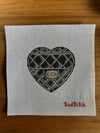 Cross-stitched heart design on fabric with 'Bad Bitch' text on a wooden surface