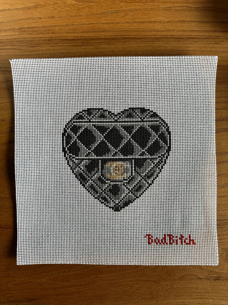 Cross-stitched heart design on fabric with 'Bad Bitch' text on a wooden surface
