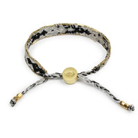 Bracelet with black and white pattern and gold accents on a white background