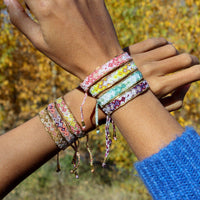 Close-up of a wrist wearing colorful bracelets with a blurred natural background
