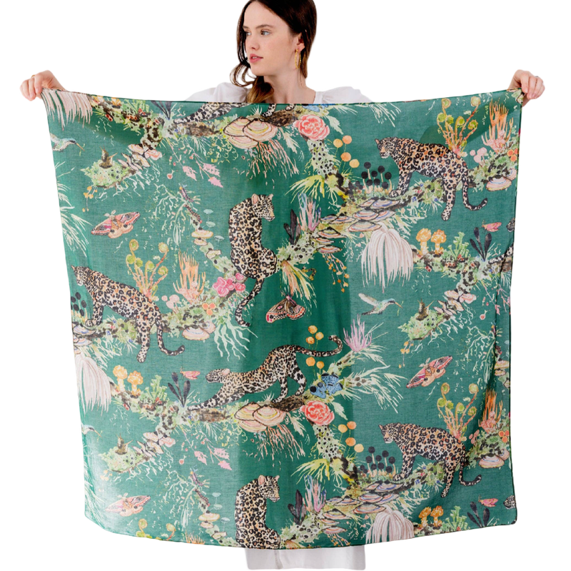 Person holding a large scarf with a jungle-themed design featuring leopards and foliage.