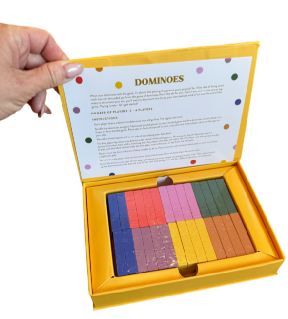 boxed dominoes game, tabletop dominoes set, stylish dominoes gift, classic domino game, colorful wooden dominoes, gold foil domino set, family game night essentials, design-focused dominoes, giftable board games, modern domino set