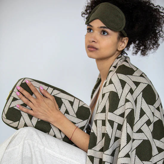 Woman holding a green and white patterned clutch with a matching headband against a plain background