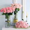 Three vases with pink roses on a decorative surface.