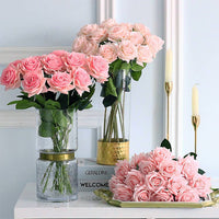 Three vases with pink roses on a decorative surface.