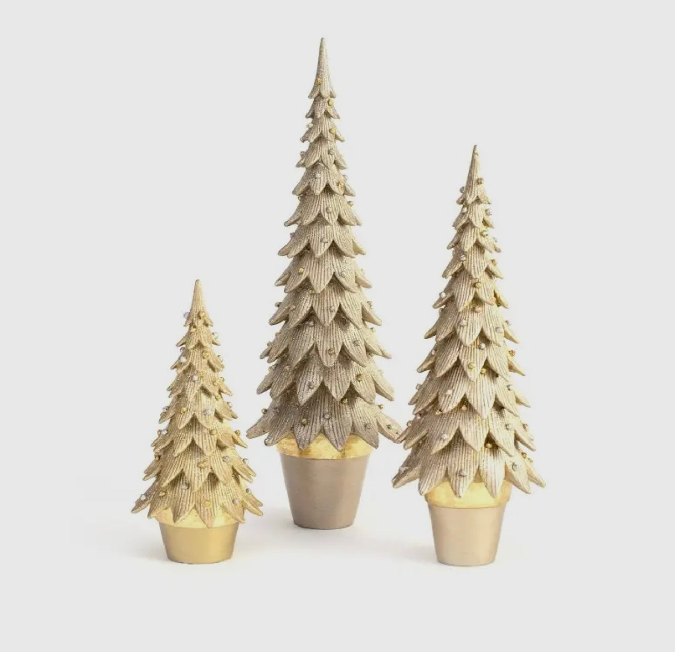 Three decorative Christmas trees with gold bases on a white background