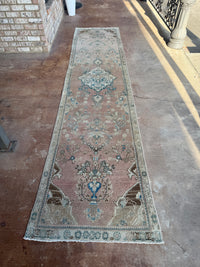 One-of-a-kind vintage Persian runner rug measuring approximately 2'11" x 12'5" with a faded dusty rose ground, blue and turquoise medallion motifs, ivory border and timeworn details.