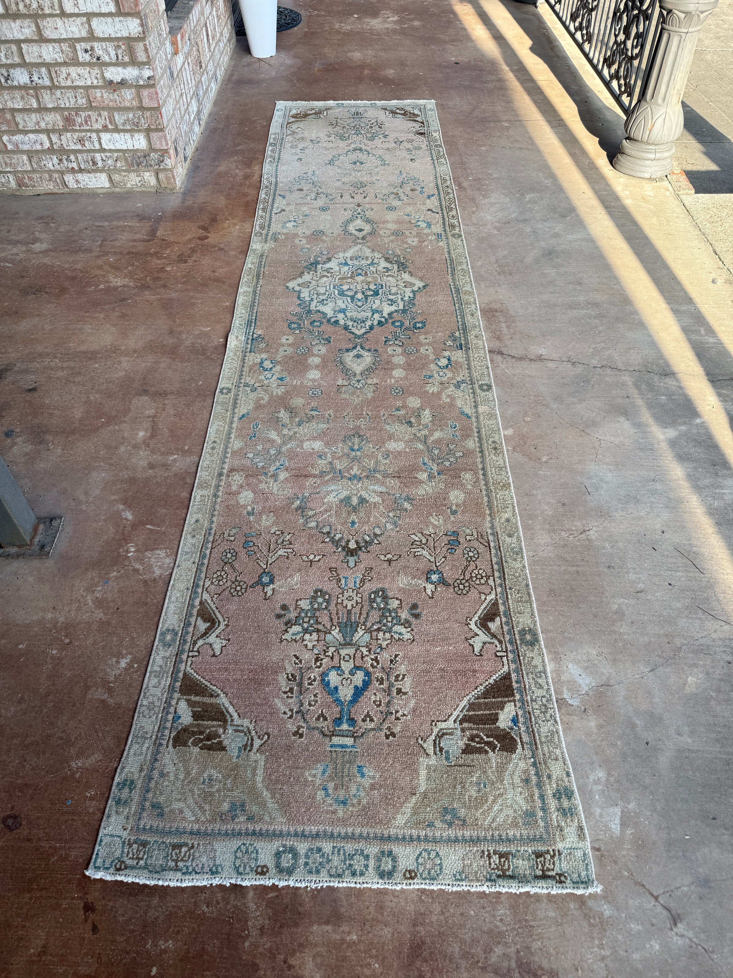 One-of-a-kind vintage Persian runner rug measuring approximately 2'11" x 12'5" with a faded dusty rose ground, blue and turquoise medallion motifs, ivory border and timeworn details.