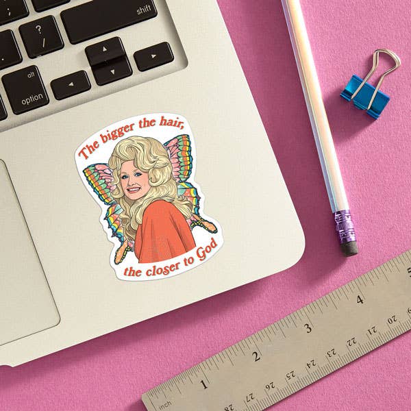 Sticker of a cartoon character with text on a laptop keyboard next to a pencil and ruler on a pink surface