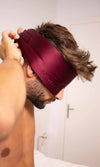 Man wearing a maroon sleep cap in a bathroom setting
