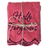 Folded pink towel with 'Hello Gorgeous' text tied with twine on a white background