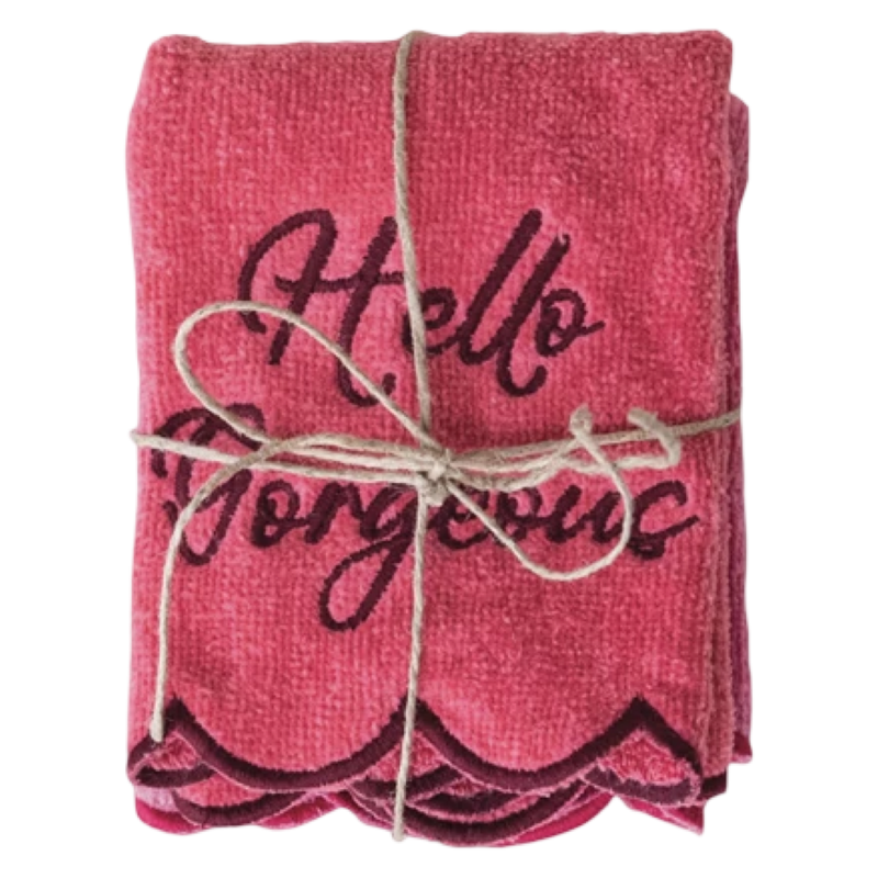 Folded pink towel with 'Hello Gorgeous' text tied with twine on a white background