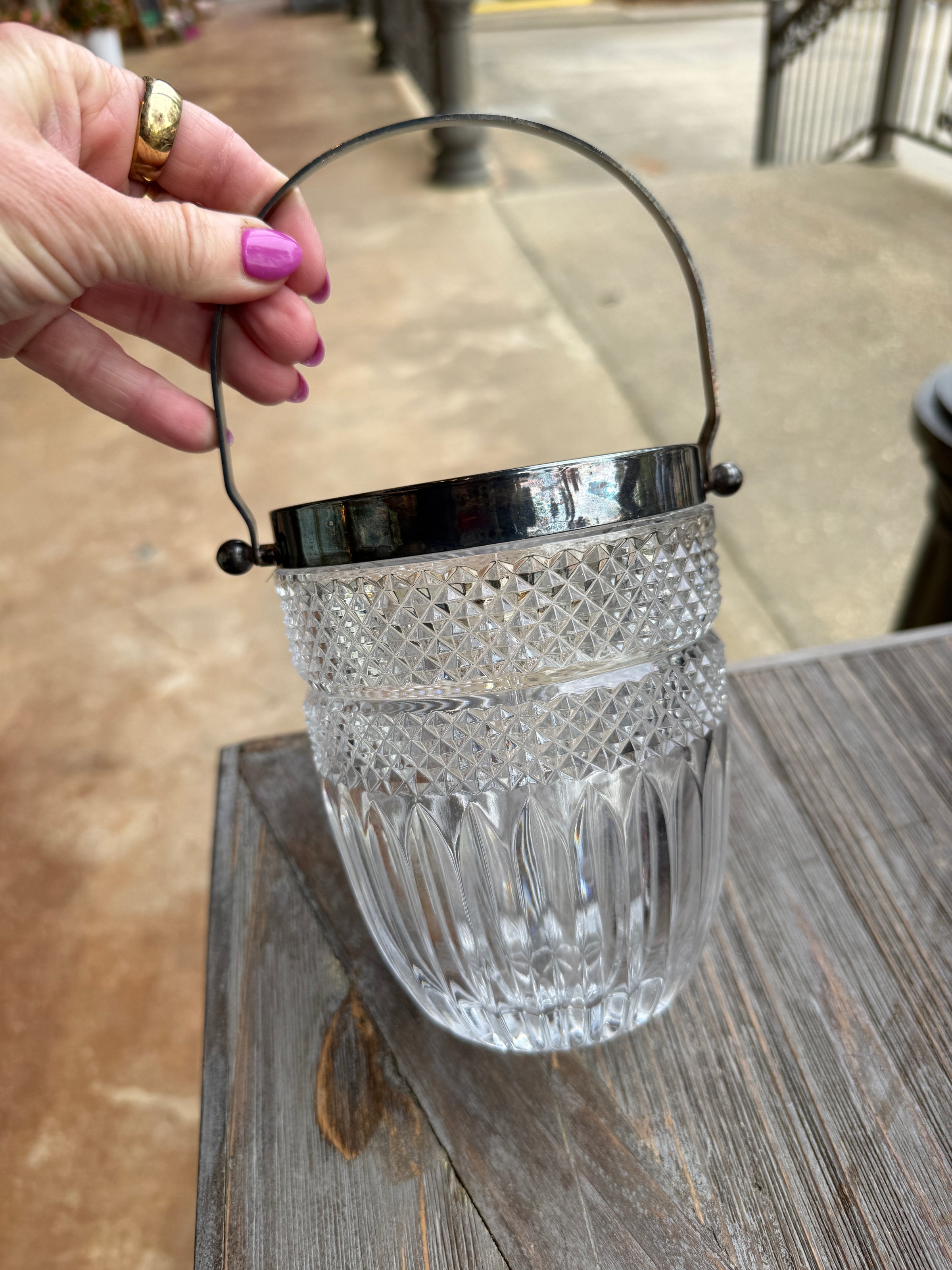 Clear glass with decorative pattern held by a hand against a wooden surface