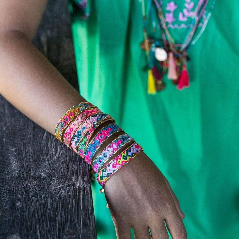 Colorful bracelets on a wrist with a green garment in the background