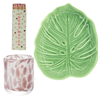 Green leaf-shaped dish, pink and white patterned candle, and 'Lucky Matches' packaging on a white background
