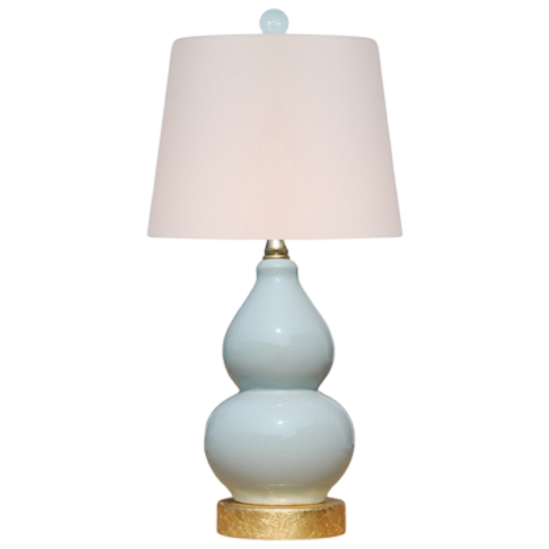 Table lamp with a white shade and light blue ceramic base on a white background