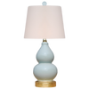 Table lamp with a white shade and light blue ceramic base on a white background