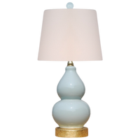 Table lamp with a white shade and light blue ceramic base on a white background