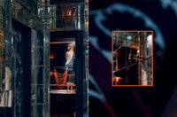 Glass display case with jewelry and a person inside, surrounded by dark and reflective surfaces.