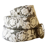 A woven belt with a textured gray base and raised off-white floral embroidery, finished with a brass buckle.