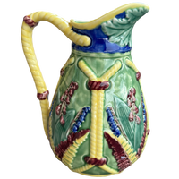 Decorative ceramic pitcher with floral patterns on a white background