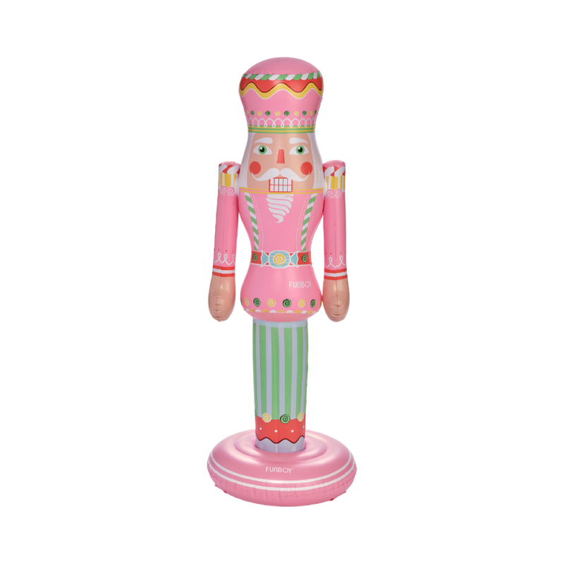Decorative nutcracker figurine with pink outfit and striped pants on a white background