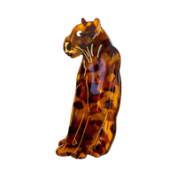 A glossy tortoiseshell cat figurine in a sitting position, featuring a marbled pattern of amber brown, black, and orange with gold-colored outlines, set against a plain white background.