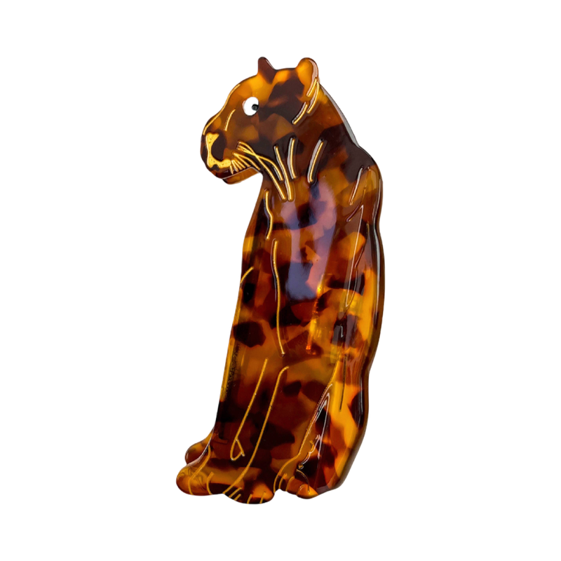 A glossy tortoiseshell cat figurine in a sitting position, featuring a marbled pattern of amber brown, black, and orange with gold-colored outlines, set against a plain white background.