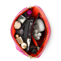 Open pink makeup bag with various cosmetic items on a white background
