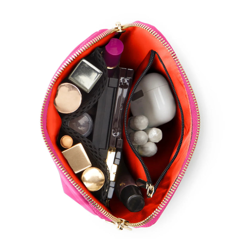 Open pink makeup bag with various cosmetic items on a white background