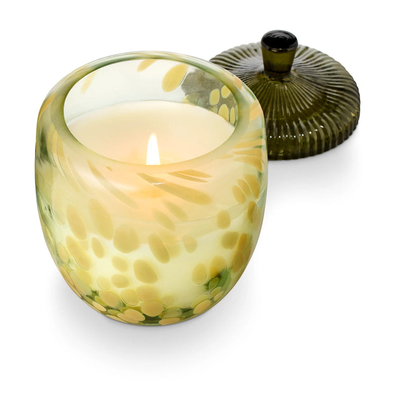 Candle in a decorative glass holder with a lid on a white background