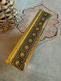Decorative gold strip with intricate patterns on a textured surface