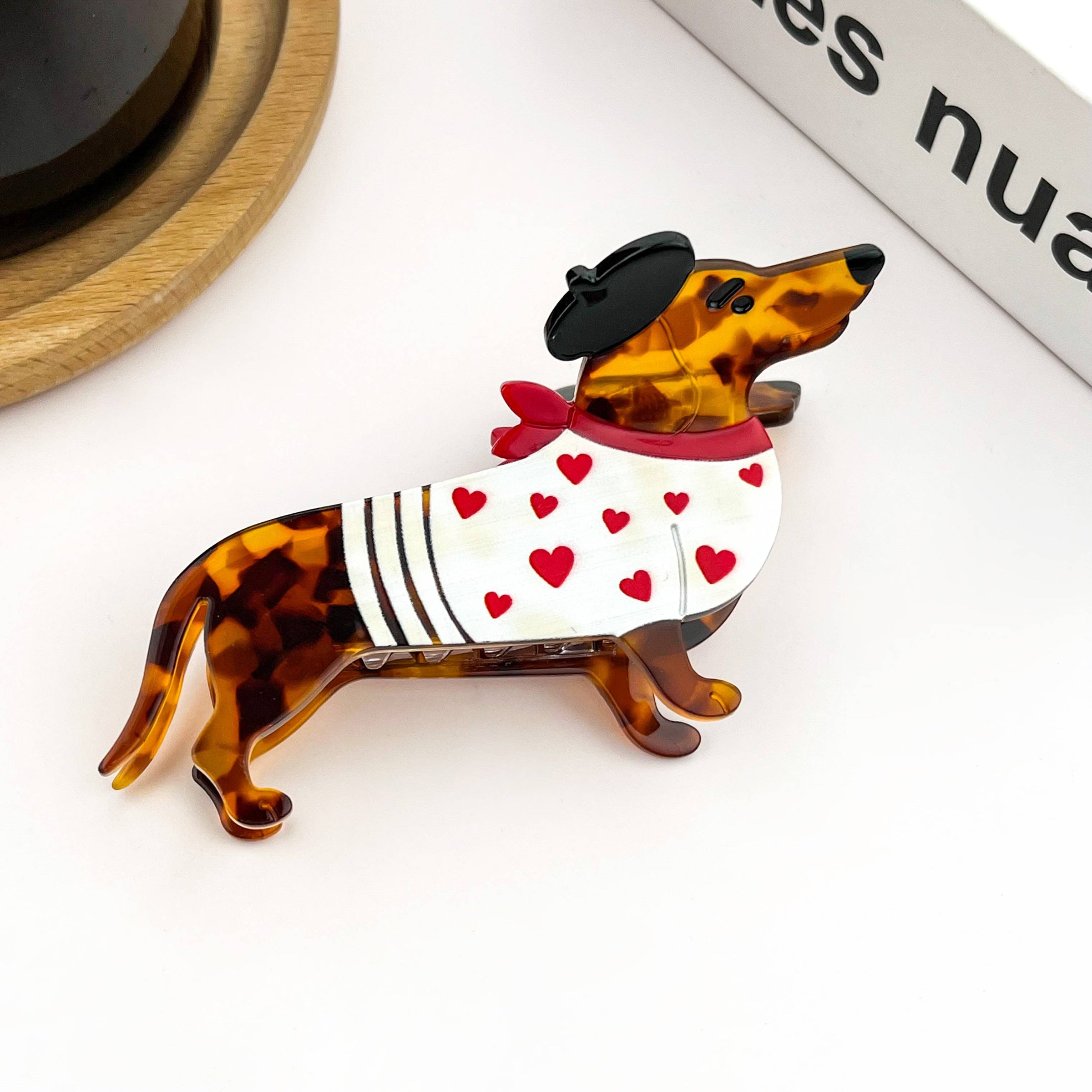 White acetate dachshund-shaped hair claw clip featuring a playful black beret detail.