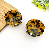 Shell-shaped earrings with tortoiseshell pattern on a white surface.