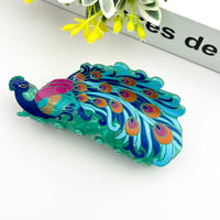 Colorful peacock-shaped hair clip on a white background