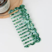 Green and white marbled hair comb on a white background