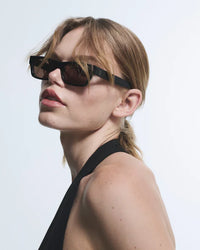 Woman wearing black sunglasses with a plain background
