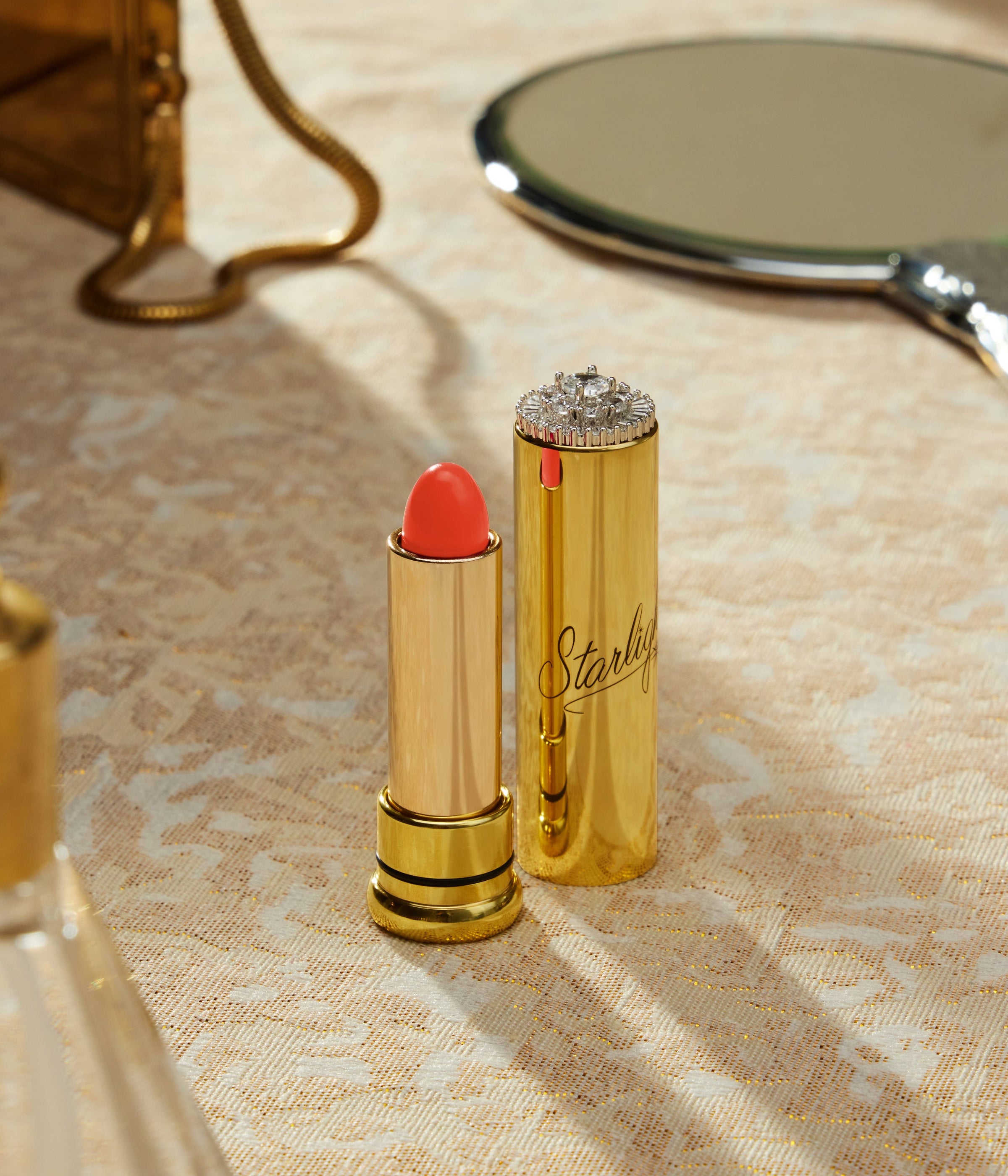Gold lipstick and case with red lipstick on a textured surface