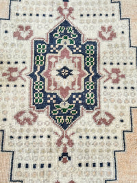 Vintage Turkish hand-knotted rug measuring approximately 3 feet 8 inches by 6 feet 4 inches with deep navy blue, cream, faded blush and green geometric medallion pattern.