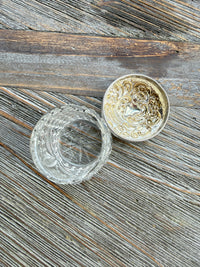 Decorative silver and glass container on a wooden surface