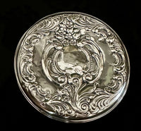 Decorative silver plate with intricate designs on a black background
