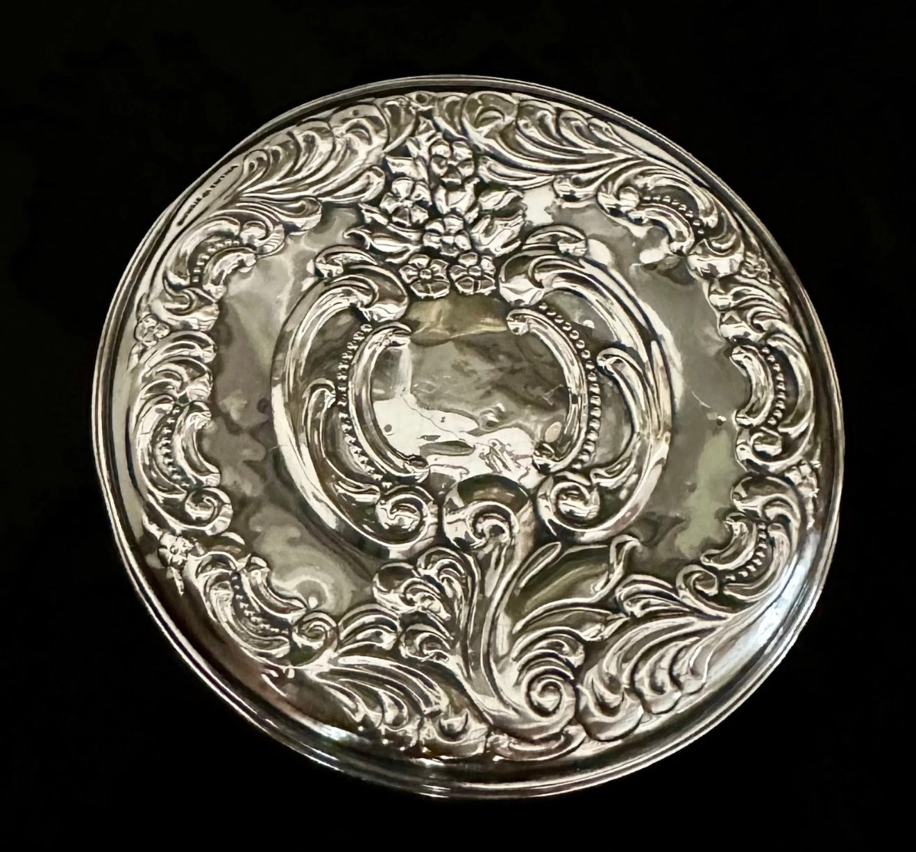 Decorative silver plate with intricate designs on a black background