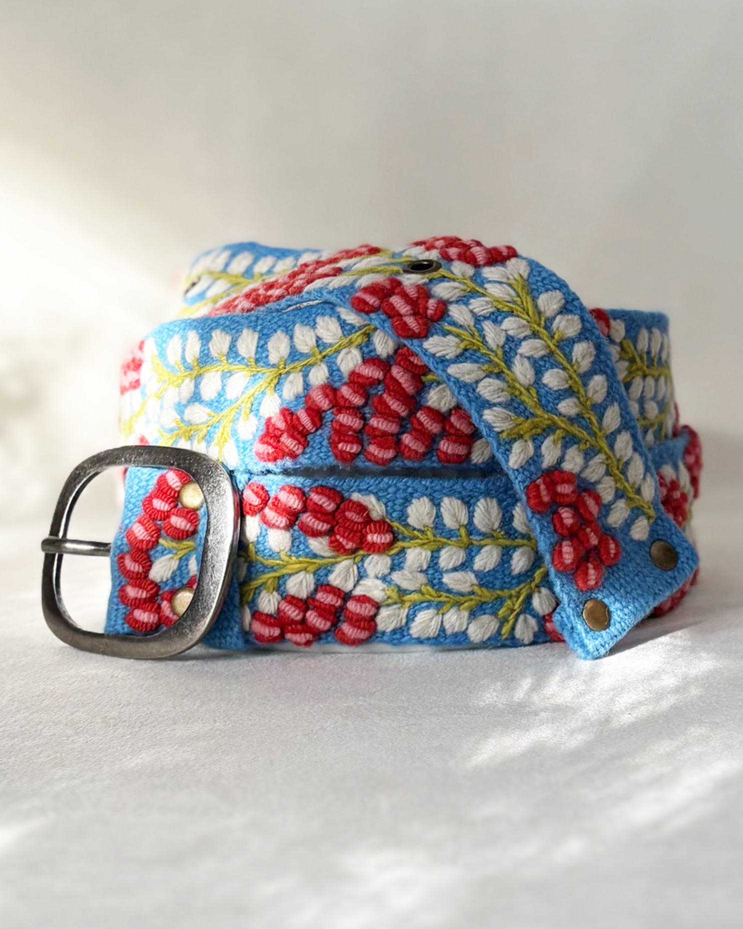 Bright blue embroidered wool belt with dimensional red berries, white leaves, green vines, and a lead-free metal buckle.
