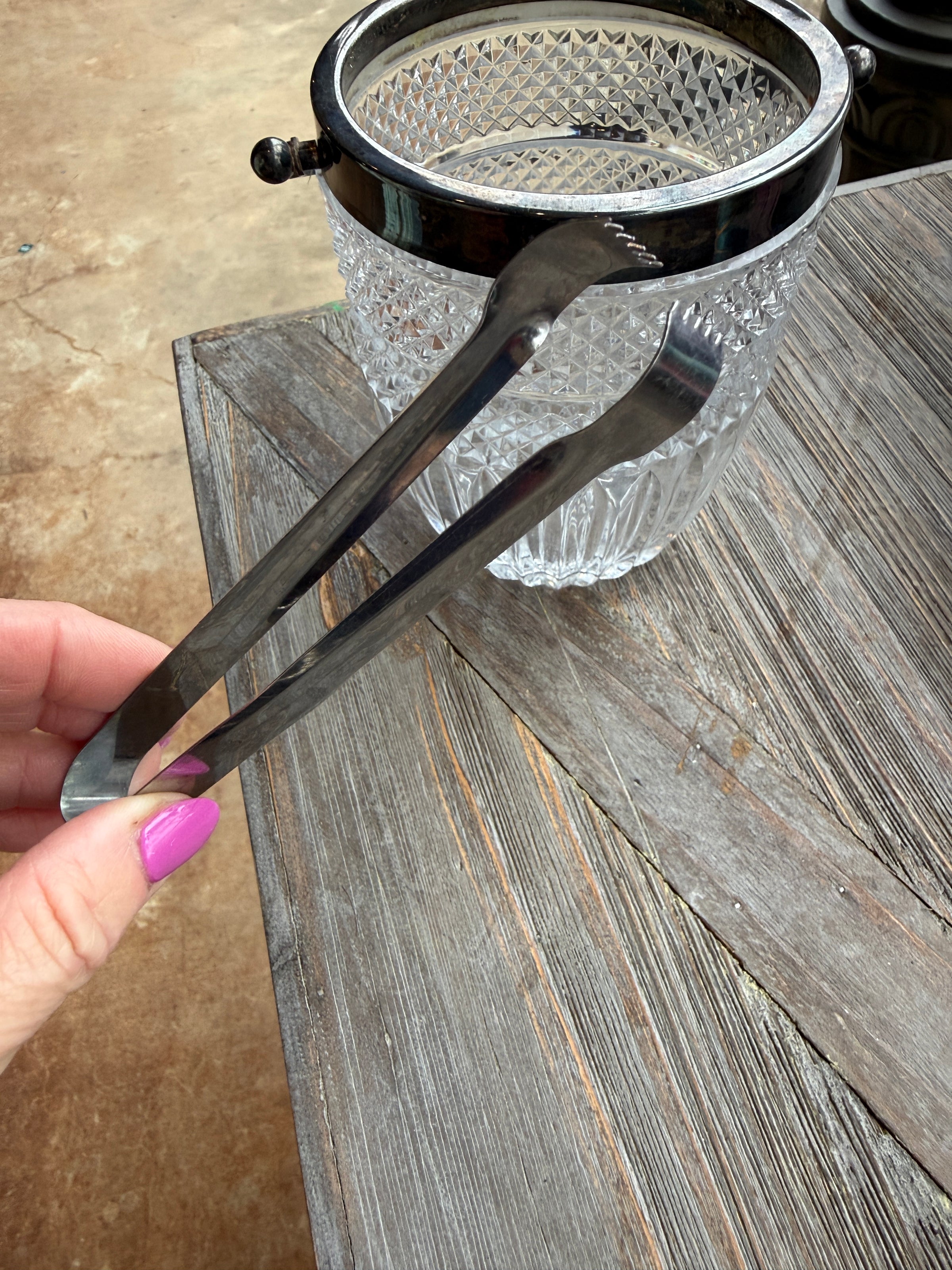 Metallic tongs held by a hand against a wooden background