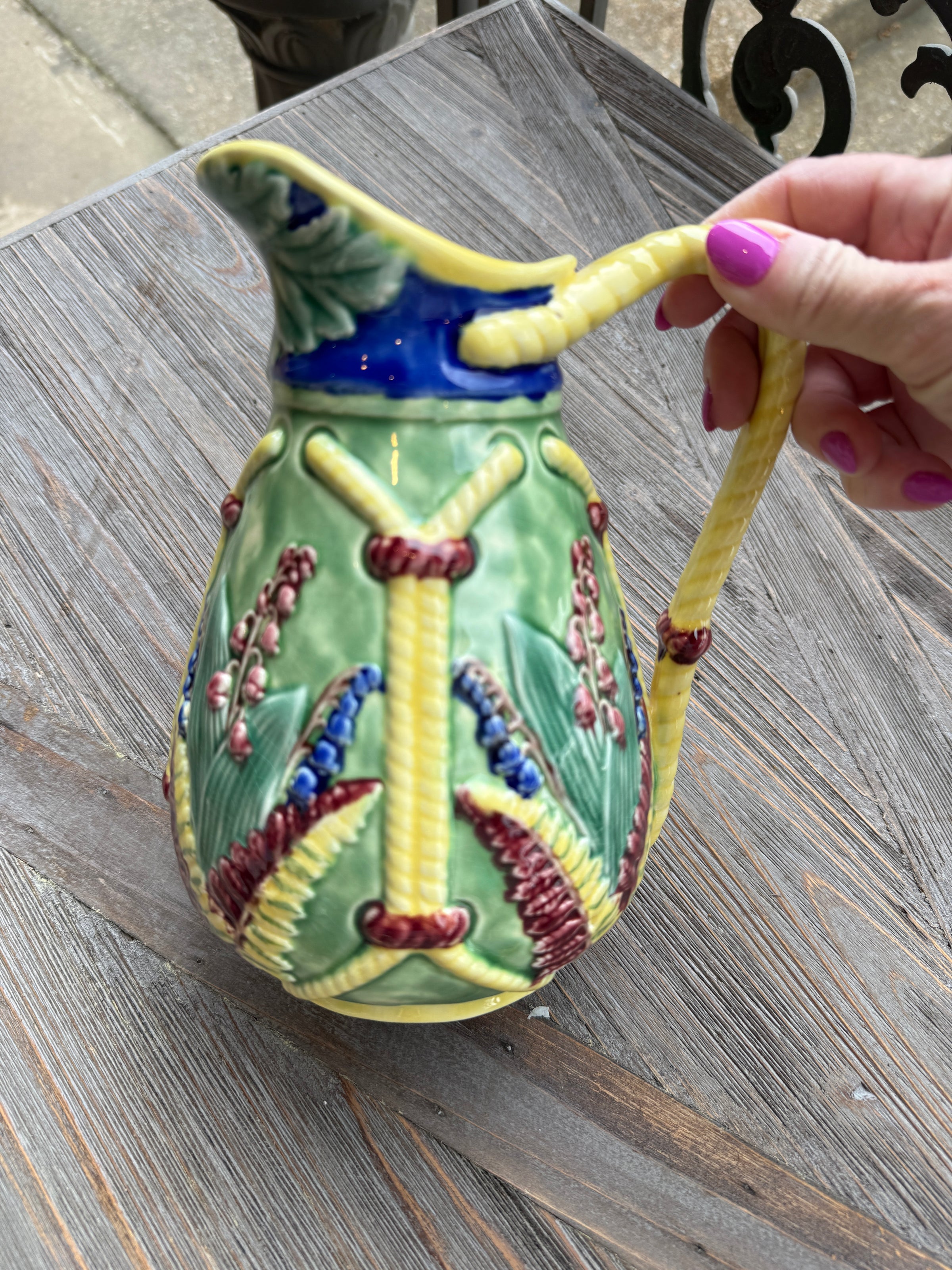 Decorative ceramic item with floral design held by a hand on a wooden surface