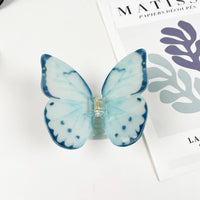Light blue acetate large butterfly-shaped hair claw clip with sculptural wings and a secure claw closure.