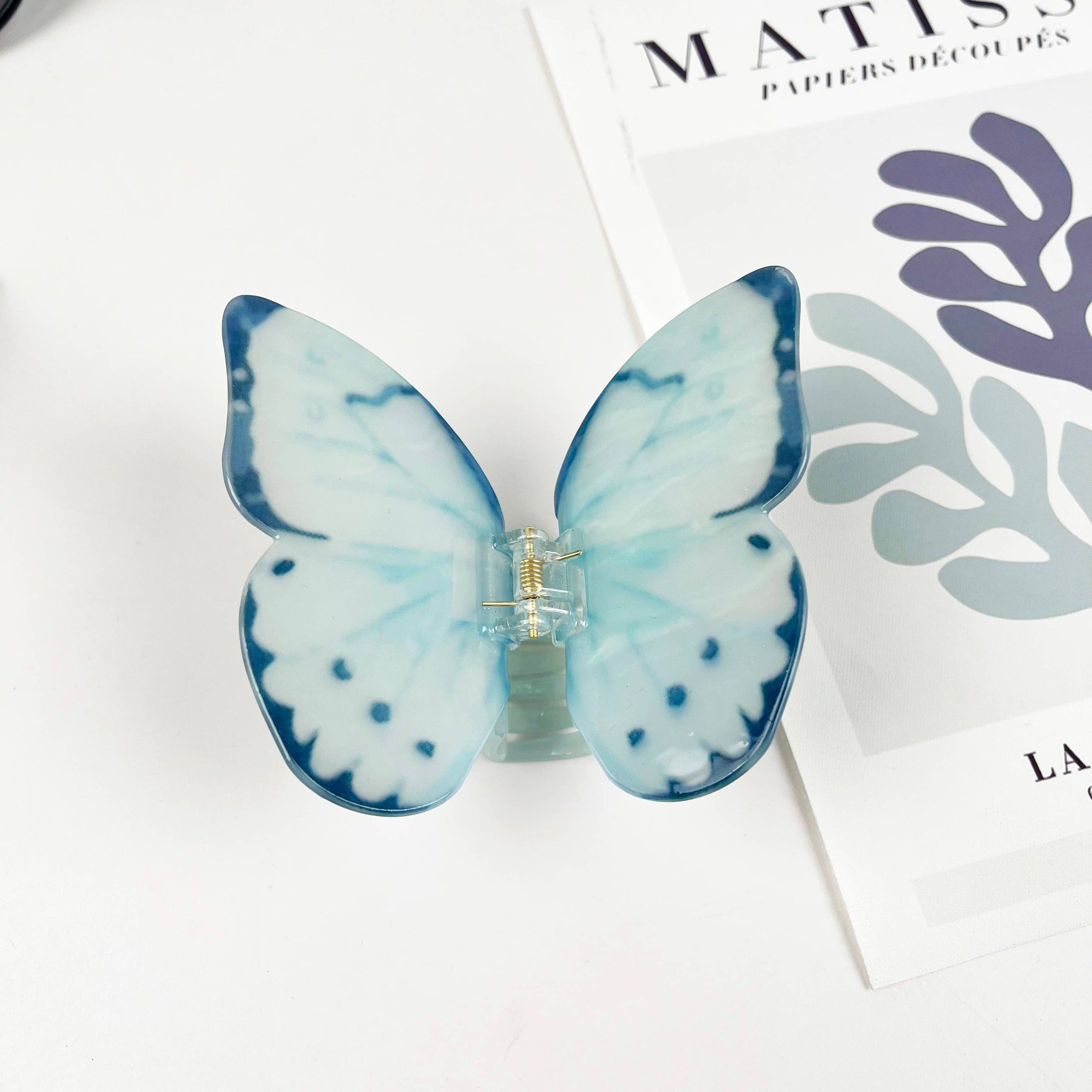 Light blue acetate large butterfly-shaped hair claw clip with sculptural wings and a secure claw closure.