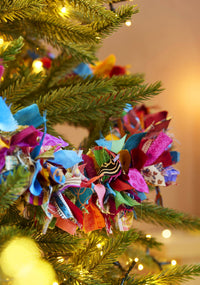 Colorful fabric flower ornament on a decorated Christmas tree.