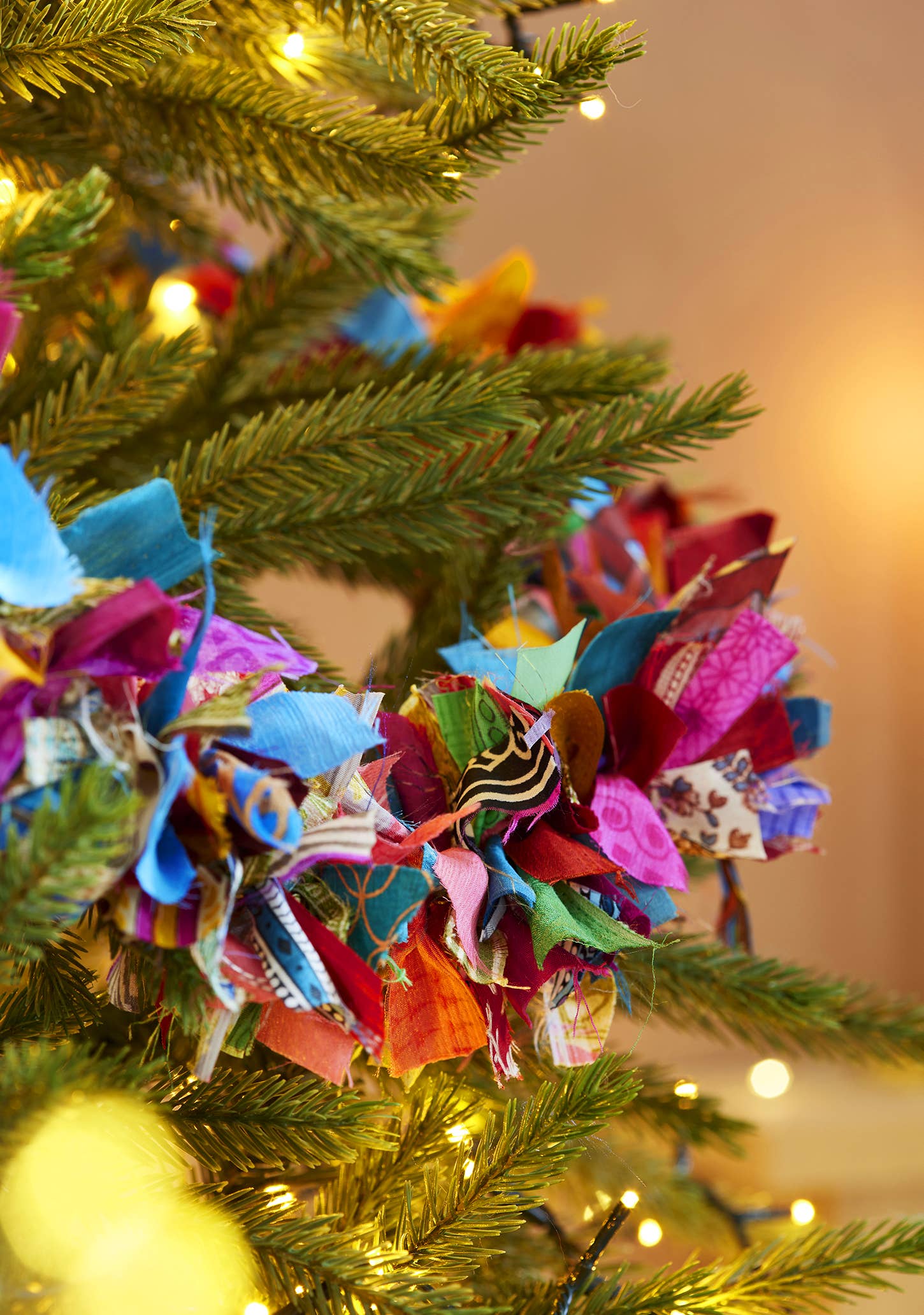 Colorful fabric flower ornament on a decorated Christmas tree.